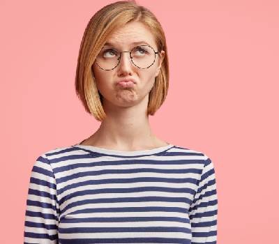 Mujer de mediana edad pelo corto rubio con lentes fondo rosa